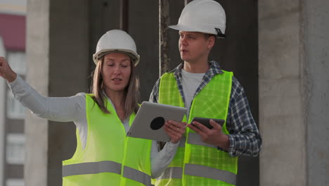 Construction-worker-and-engineer-talking-at-construction-site-site.-Workers-in-helmets-at-building-area.-Portrait-of-construction-engineers-working-on-building-site.-concept-of-modern-construction